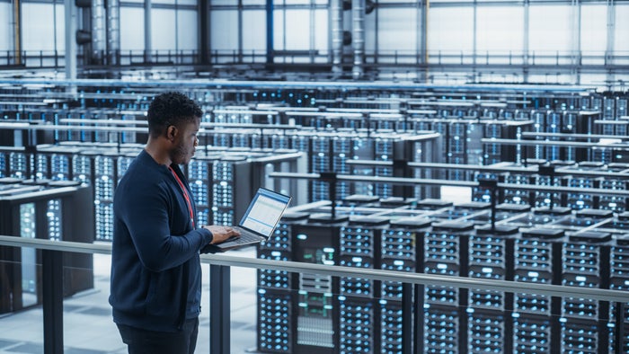 Person reviewing their laptop inside a data center.