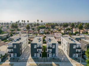 10 unit Multi-Family property on La Brea Ave., Los Angeles, CA.  Gray and white building, surrounded by palm trees.  Sunny California weather.