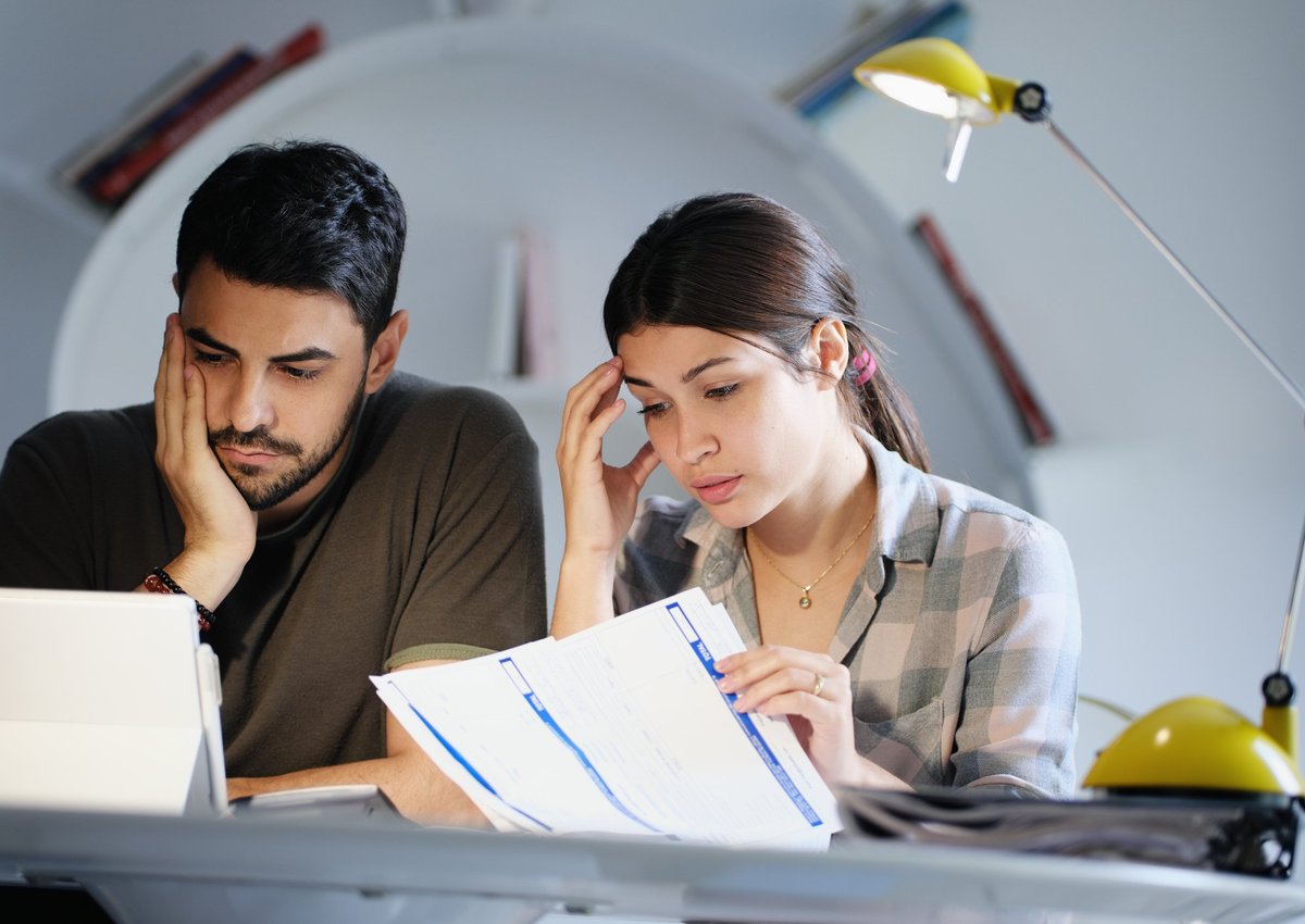 A young couple looking stressed while reviewing their bills.