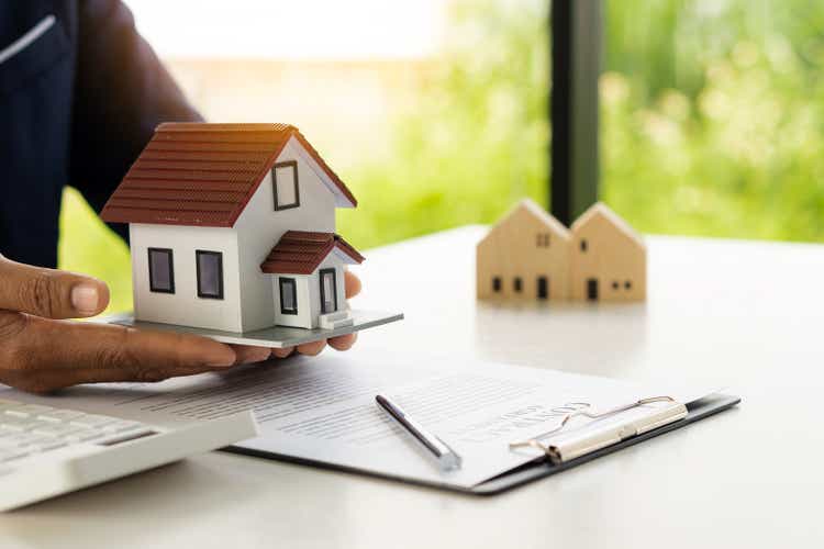 A real estate agent offers a sample home insurance home to sign the agreement.  with documents of the contract of sale or lease
